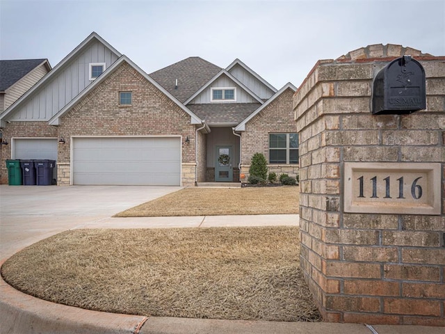 craftsman inspired home with a garage, concrete driveway, roof with shingles, board and batten siding, and brick siding