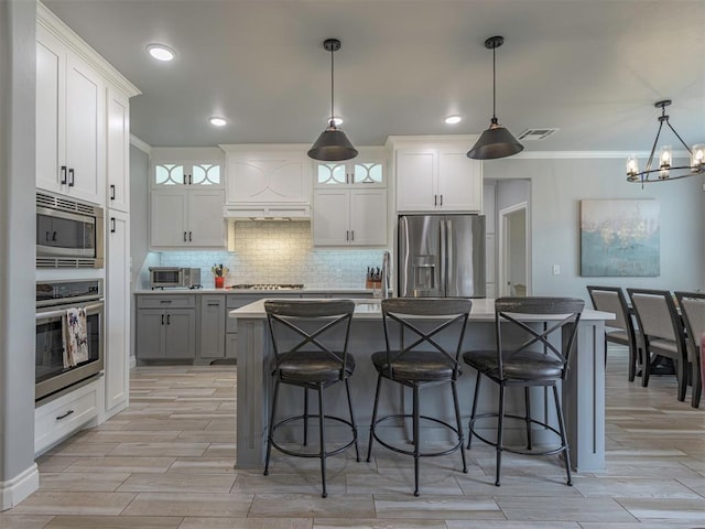 kitchen with tasteful backsplash, glass insert cabinets, stainless steel appliances, and a kitchen breakfast bar