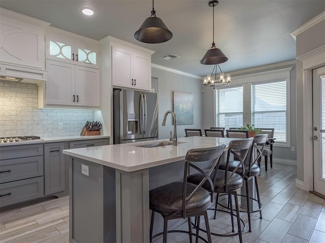 kitchen with decorative backsplash, stainless steel appliances, crown molding, light countertops, and a sink