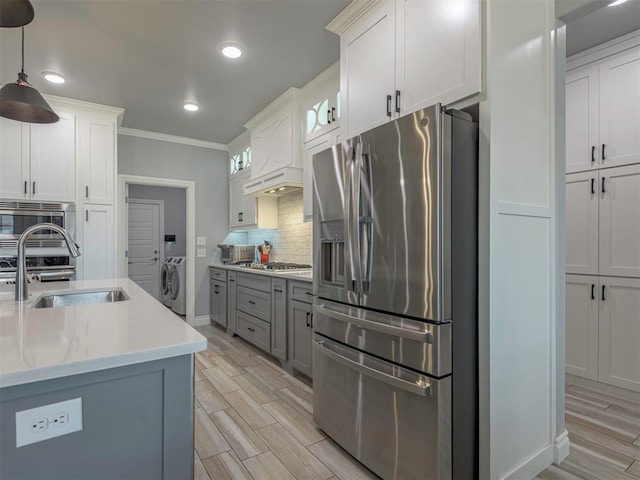 kitchen featuring wood finish floors, tasteful backsplash, light countertops, appliances with stainless steel finishes, and a sink