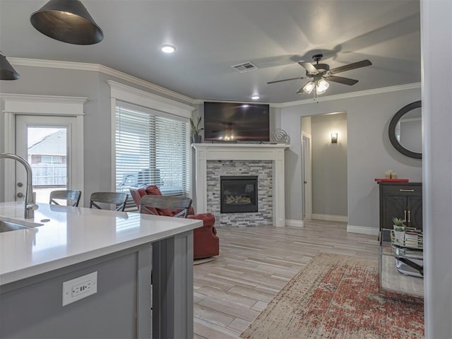 living area featuring a healthy amount of sunlight, a fireplace, visible vents, and ornamental molding