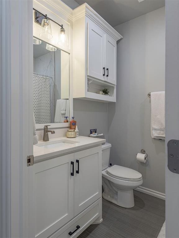 full bath featuring curtained shower, baseboards, vanity, and toilet