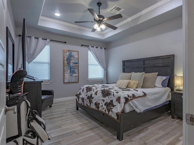 bedroom with light wood-style floors, visible vents, and a raised ceiling