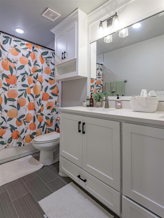 bathroom with toilet, vanity, and visible vents