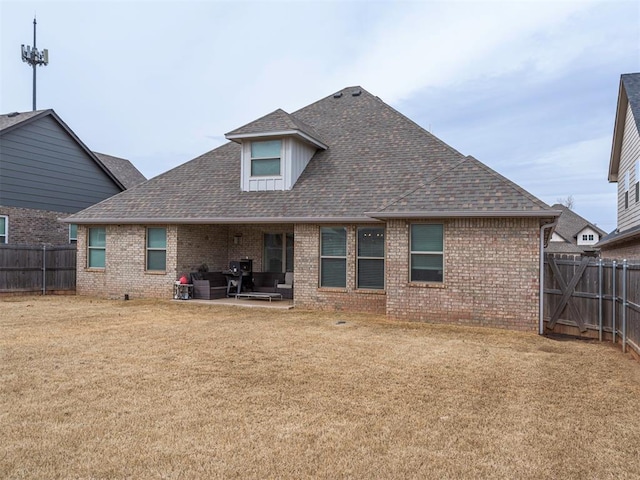 rear view of property featuring a shingled roof, a patio, a fenced backyard, a yard, and brick siding