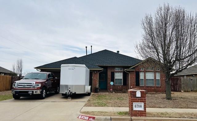 view of front facade with brick siding, concrete driveway, and fence