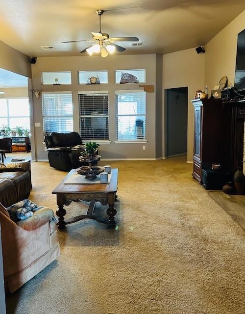 living room featuring visible vents, baseboards, light colored carpet, and ceiling fan