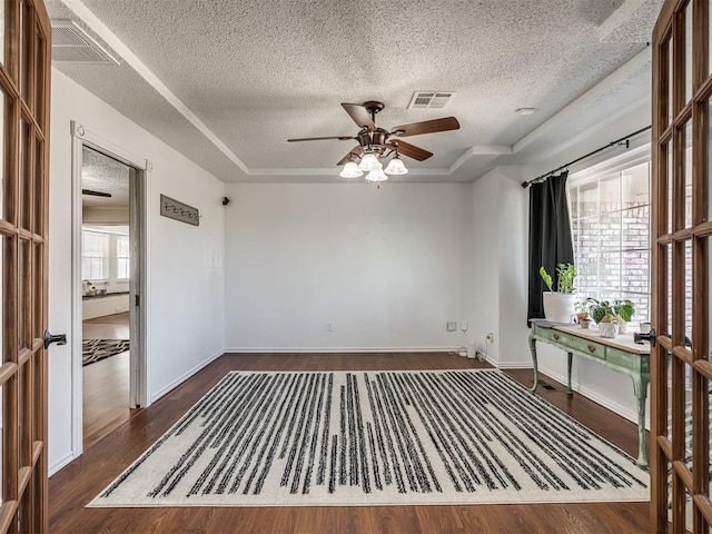 empty room with visible vents, baseboards, dark wood-type flooring, and a ceiling fan