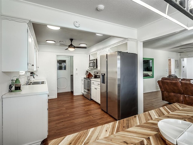 kitchen with a ceiling fan, a sink, stainless steel appliances, white cabinetry, and open floor plan