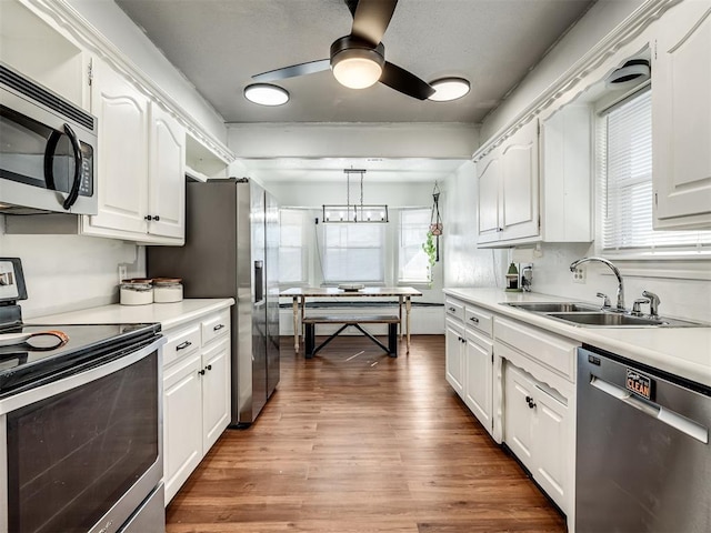 kitchen featuring a sink, wood finished floors, stainless steel appliances, white cabinets, and light countertops