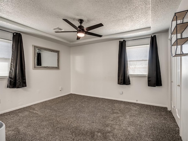 carpeted empty room with baseboards, visible vents, a textured ceiling, and a ceiling fan