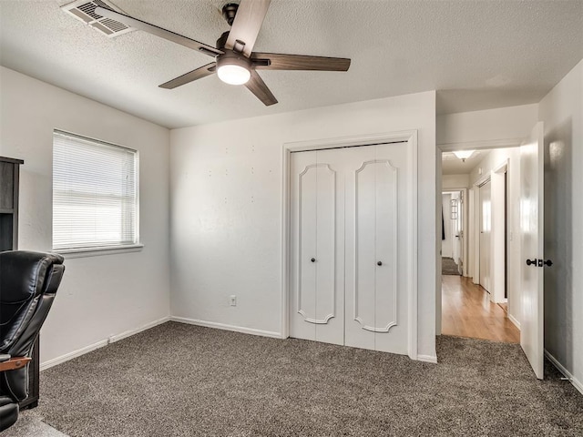 interior space with visible vents, a textured ceiling, a closet, carpet, and baseboards