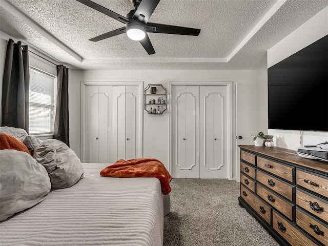 bedroom with ceiling fan, a textured ceiling, two closets, and carpet