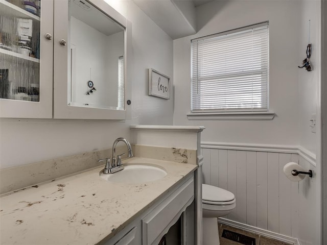 bathroom with wainscoting, toilet, and vanity