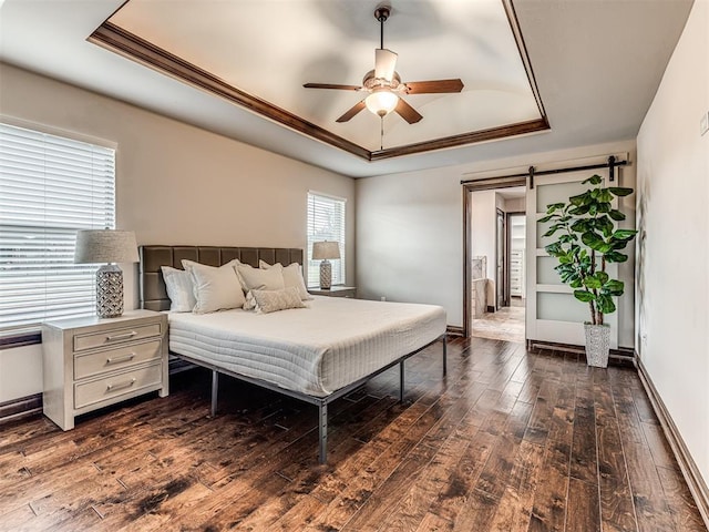 bedroom featuring a raised ceiling, baseboards, dark wood-style flooring, and a barn door