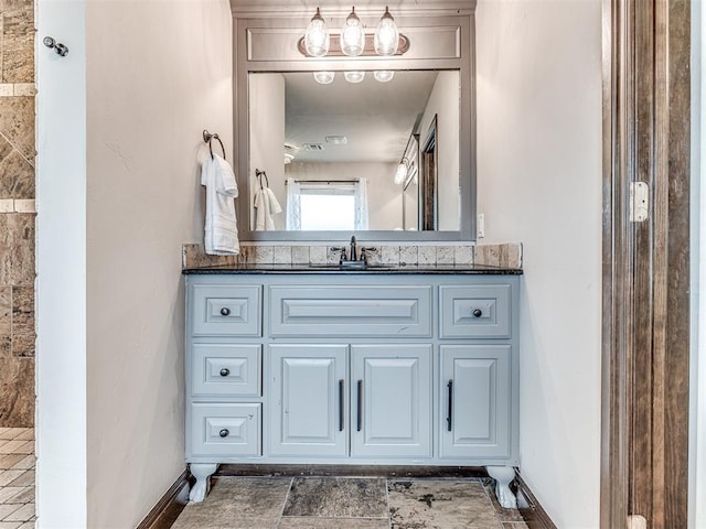 bathroom with stone finish floor, baseboards, and vanity