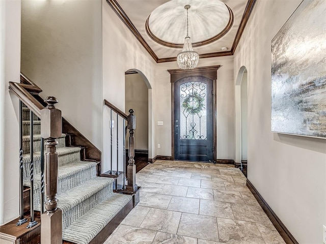 entryway featuring ornamental molding, arched walkways, a notable chandelier, and baseboards