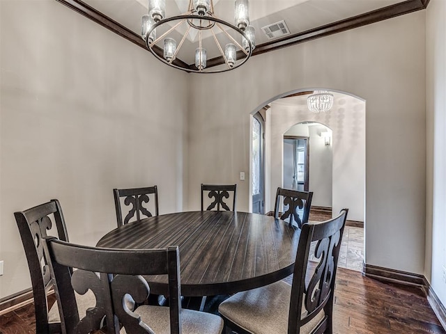 dining area featuring arched walkways, visible vents, ornamental molding, dark wood finished floors, and an inviting chandelier