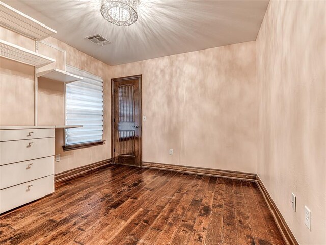 unfurnished room featuring baseboards, visible vents, and dark wood finished floors