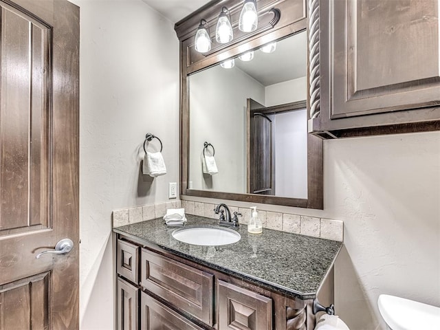 bathroom with toilet, a textured wall, and vanity