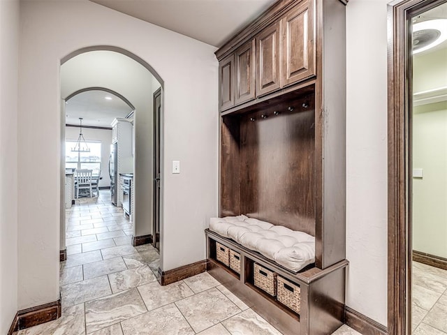 mudroom featuring arched walkways and baseboards