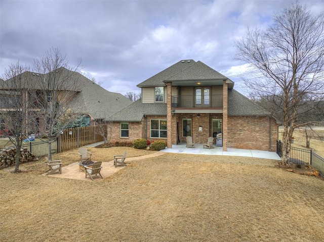 view of front of property with brick siding, a patio area, a balcony, a fenced backyard, and a fire pit