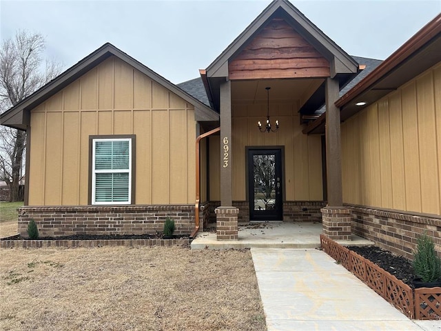 property entrance with roof with shingles, brick siding, and board and batten siding