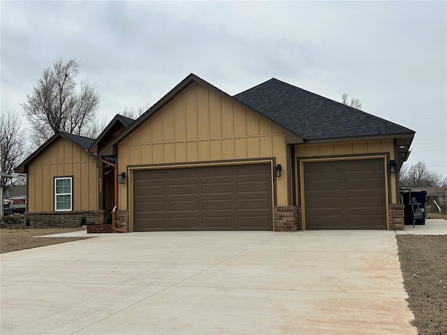 ranch-style home featuring an attached garage, brick siding, concrete driveway, roof with shingles, and board and batten siding