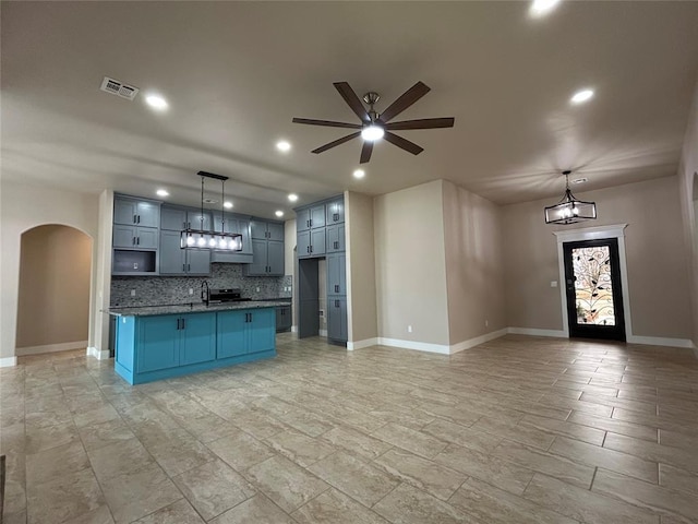 kitchen featuring tasteful backsplash, visible vents, arched walkways, open floor plan, and hanging light fixtures