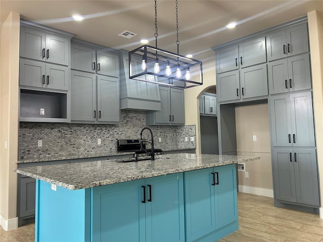 kitchen featuring arched walkways, stone counters, a sink, and backsplash