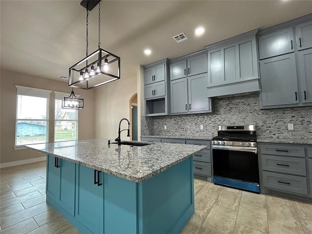 kitchen featuring stainless steel range with gas cooktop, decorative backsplash, a sink, and gray cabinetry