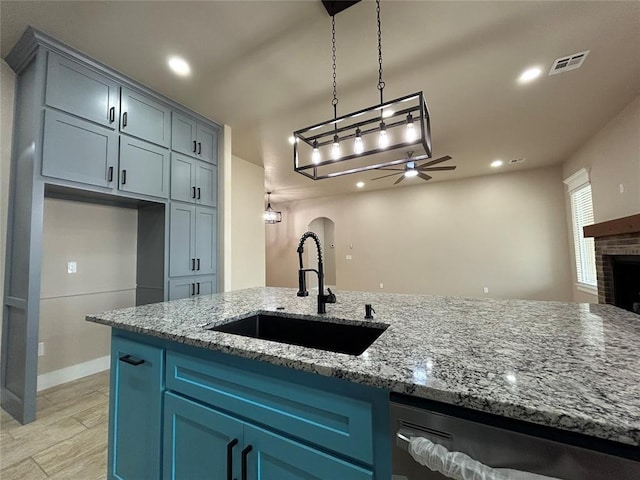 kitchen with arched walkways, a fireplace, a ceiling fan, a sink, and dishwashing machine