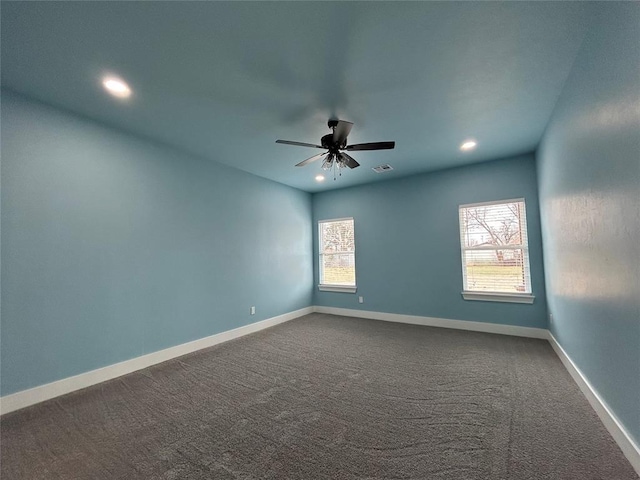 empty room with ceiling fan, baseboards, visible vents, and dark carpet