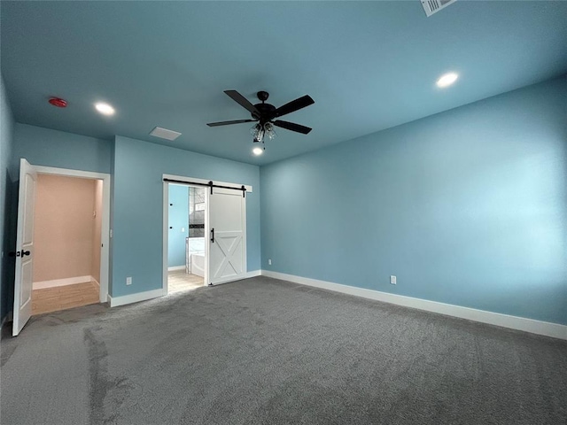 unfurnished bedroom featuring a barn door, connected bathroom, recessed lighting, carpet flooring, and baseboards