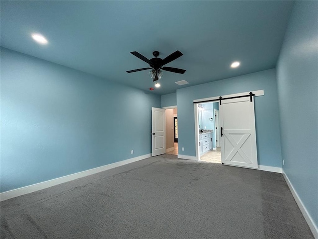 unfurnished bedroom featuring ceiling fan, a barn door, recessed lighting, carpet flooring, and baseboards