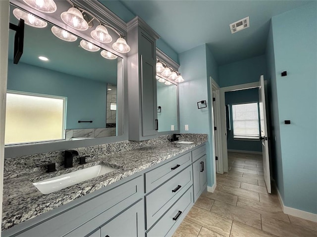 bathroom featuring double vanity, a sink, visible vents, and baseboards