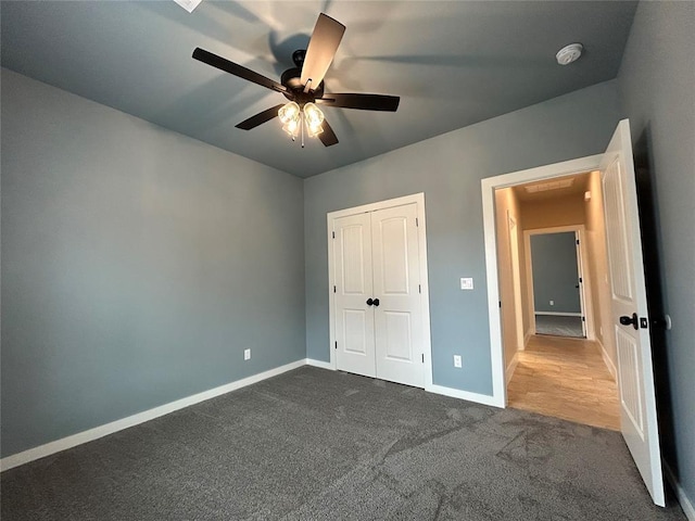 unfurnished bedroom with a ceiling fan, baseboards, dark colored carpet, and a closet