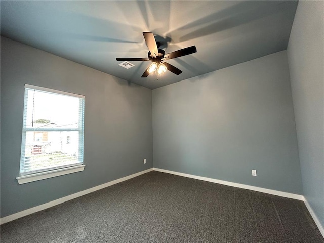 unfurnished room featuring baseboards, visible vents, dark carpet, and a ceiling fan