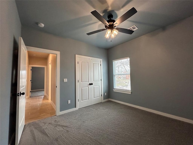 unfurnished bedroom featuring ceiling fan, carpet, visible vents, and baseboards