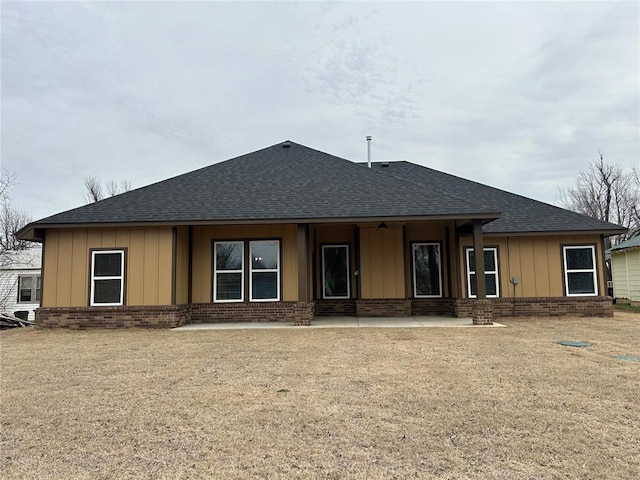 back of property with a shingled roof, board and batten siding, and brick siding