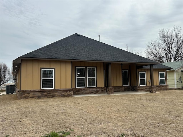 rear view of property with roof with shingles, brick siding, board and batten siding, and cooling unit