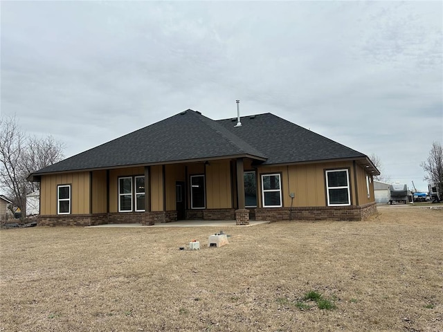 rear view of property with roof with shingles, brick siding, and board and batten siding