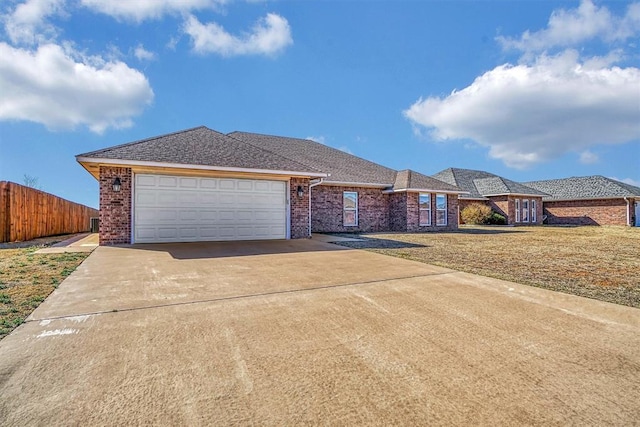 view of front of property with an attached garage, fence, concrete driveway, and brick siding