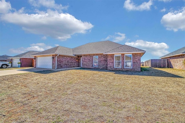 ranch-style home with brick siding, an attached garage, a front yard, fence, and driveway