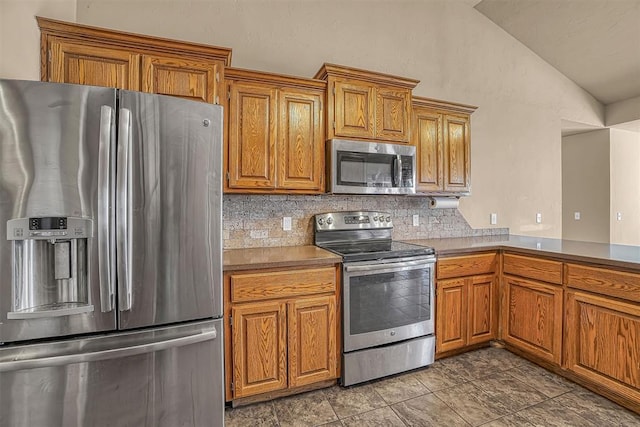 kitchen featuring vaulted ceiling, appliances with stainless steel finishes, and brown cabinets