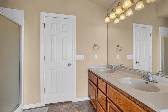 bathroom with double vanity, a sink, baseboards, and an enclosed shower