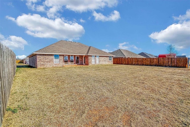 back of property with fence, a lawn, and brick siding