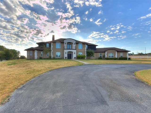 view of front of home featuring driveway, a chimney, a front lawn, and fence