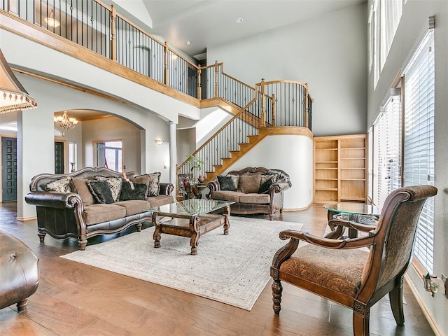 living area featuring a wealth of natural light, a notable chandelier, a high ceiling, and stairs