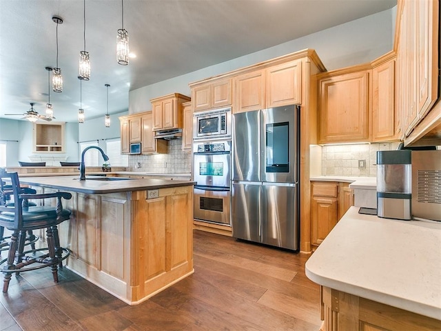 kitchen featuring light brown cabinets, appliances with stainless steel finishes, a sink, and dark wood finished floors